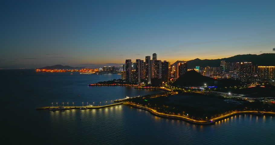 Aerial shot of a city skyline with modern buildings along the coast at night in Shenzhen, China.