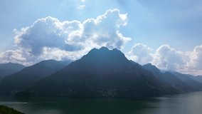Aerial view of layered mountain silhouettes with rays of light piercing dramatic clouds above tranquil lake. Shot at Riva di Solto, Lombardy, Italy (Riva di Solto, Lombardia) - Powered by Shutterstock - Get 15% off with code: PIKWIZARD15