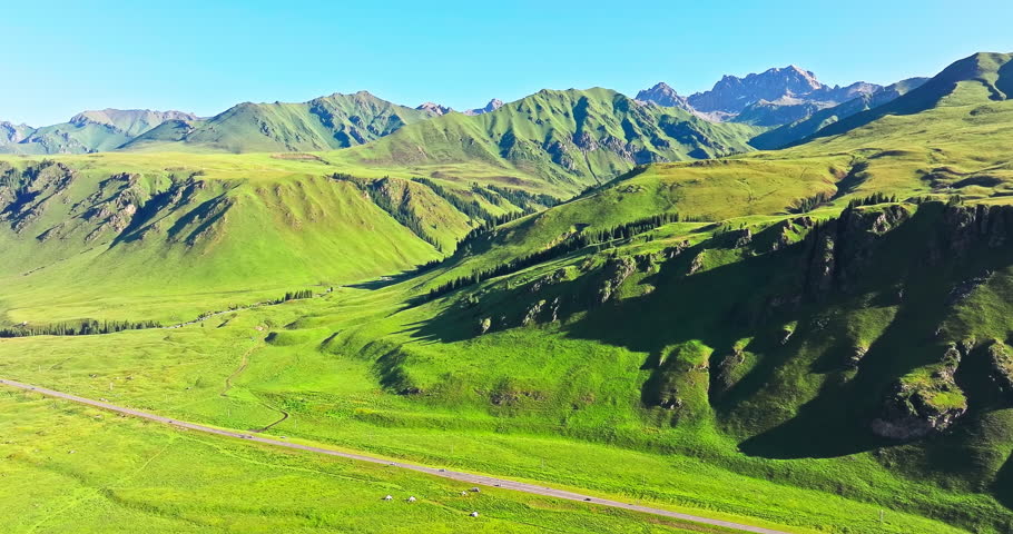 Aerial shot of the green meadow and mountain natural landscape in summer. Beautiful mountain range scenery in Xinjiang, China.