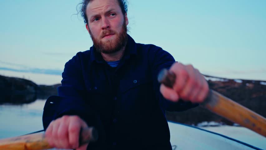 A Caucasian Man With A Beard Is Rowing A Boat Over A Lake. Close-up Shot