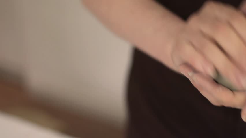 Close-up of female hands forming a clay ball during the pottery process. Craftsmanship, handmade art, and tactile connection to traditional ceramic techniques.