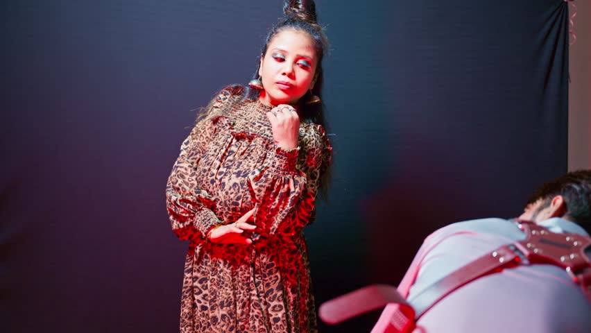 Model wears wild pattern outfit with flair in studio, Cameraman records bold talent inside photo venue, Photographer lead woman through lively stance, Modeling shoots with vivid brightness setup, Icon