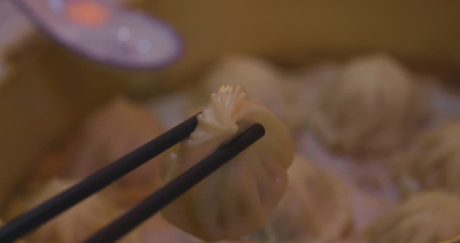 Xiao long bao in the steamer basket with chopsticks at dinner handheld shot