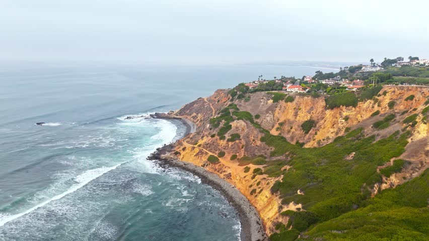 Aerial crane shot of Bluff Cove, Palos Verdes Estates, California on an overcast day revealing beautiful homes atop of the dramatic cliffs