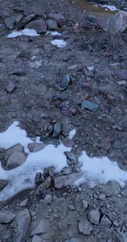Sacred Gumbo Ronjon mountain in Zanskar Valley, Ladakh, with melting stream and snow-covered winter landscape under cloudy sky