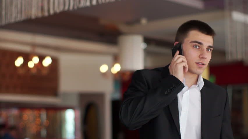 Young businessman talking on the phone and smiling at camera
