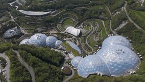 Sweeping aerial of translucent Eden Project domes nestled amid spiral paths, tiered vegetation and surrounding woodland in a reclaimed Cornish quarry - Powered by Shutterstock - Get 15% off with code: PIKWIZARD15