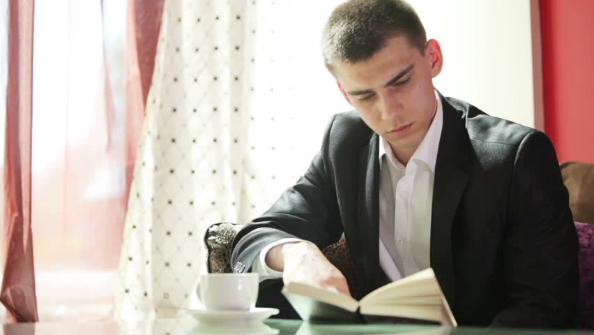 Young businessman drinking coffee and reading a book

