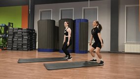 Two Caucasian women doing burpees in a fitness center.  - Powered by Shutterstock - Get 15% off with code: PIKWIZARD15