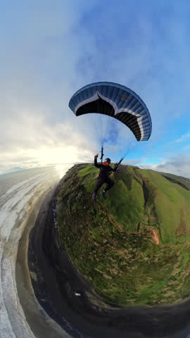 Extreme paragliding pilot soaring in the New Zealand beach at sunset. Adventure concept