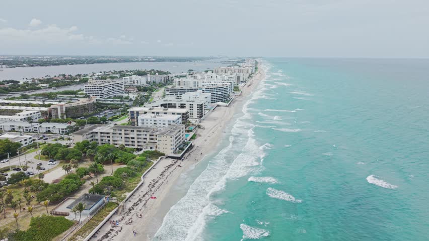 Establishing drone shot of beach and hotels next to Atlantic Ocean with cloudy weather during the day in West Palm Beach, Florida, USA