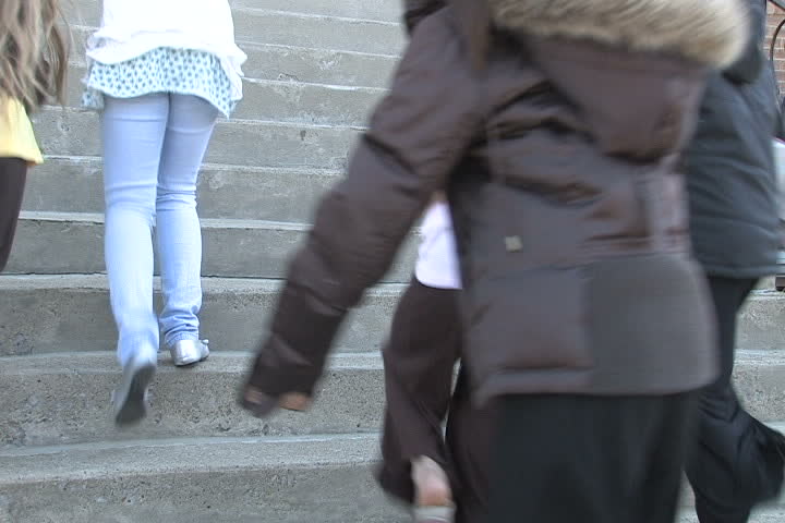 Kids run up the steps into school.