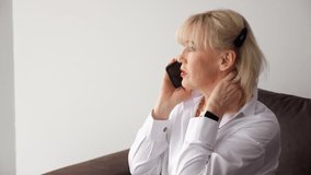 Senior businesswoman wearing white shirt during phone conversation, sitting comfortably on sofa with professional and relaxed demeanor - Powered by Shutterstock - Get 15% off with code: PIKWIZARD15