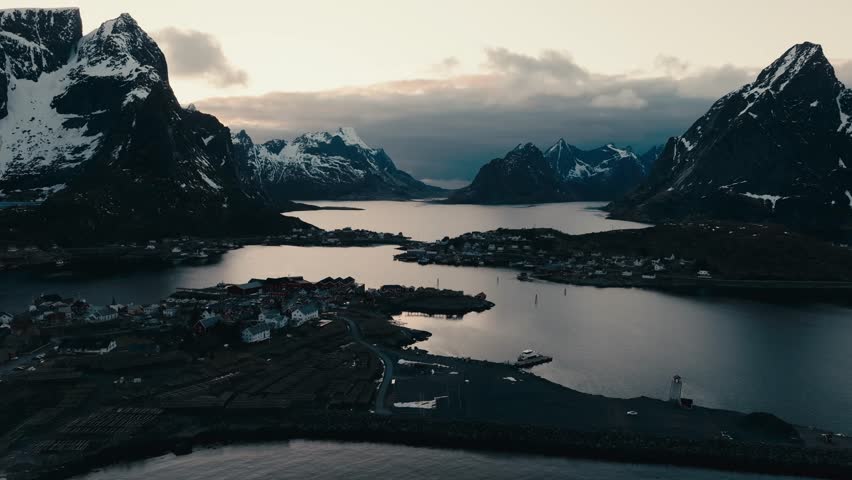 Aerial View Of Reine, Lofoten, Norway - Snow-capped Mountains And Village On Island Of Moskenesoya At Sunset.