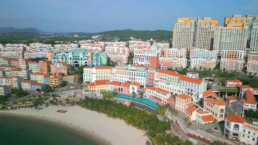 Aerial view of Sunset Town in Phu Quoc, Vietnam, showcasing pastel-colored European-style buildings, beach, and palm trees under a clear blue sky.