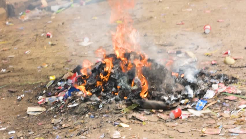 A dangerous roadside fire ignites on piled garbage, emitting thick toxic smoke and causing severe air pollution in the city, highlighting environmental hazards.