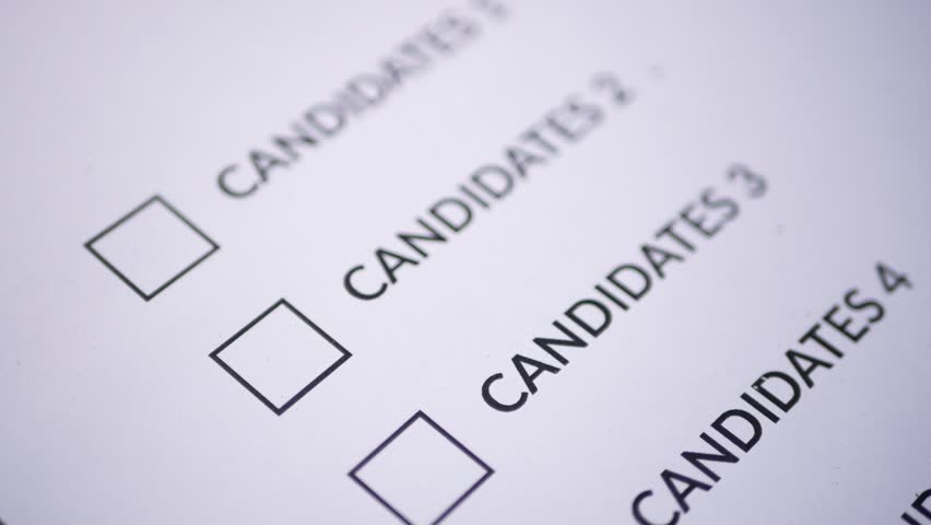 a person's hand holding a pen for marking a x cross on ballots to vote for a candidate. candidate election concept