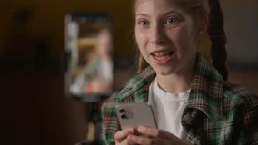 Excited little girl blogger filming blog review mobile phone smartphone camera influencer child Caucasian kid vlogger schoolgirl play online game talk opinion typing cellphone recording tripod at home - Powered by Shutterstock - Get 15% off with code: PIKWIZARD15
