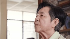 Elderly woman wearing a hearing aid at home, adjusting the device to improve hearing. Natural light and indoor setting highlight independent senior care and daily use of assistive technology. - Powered by Shutterstock - Get 15% off with code: PIKWIZARD15