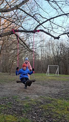 boy and girl swinging on a homemade swing tied to a tree, autumn, spring in Europe, friendship of a boy and a girl