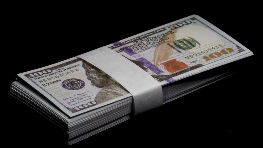 A stack of 100 hundred-dollar bills on a black background with beautiful lighting, 360-degree rotating video. 4k video.