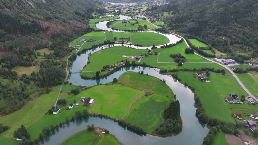 An aerial view of the landscape and green forest of rural houses by Stryn River, in Stryn, Norway