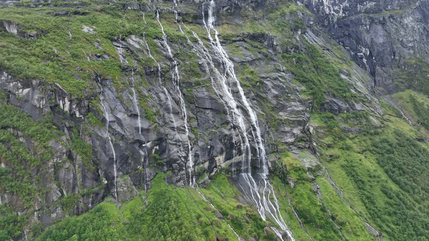 Thin waterfalls cascade down the rocky cliffs of Vikagjolet Fossen in Loen, Norway lush landscape