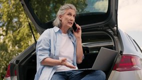 Annoyed confused irritated Caucasian grandmother aged business woman female mature businesswoman using laptop problem broken computer trouble speak mobile phone searching pc at park sitting car trunk - Powered by Shutterstock - Get 15% off with code: PIKWIZARD15