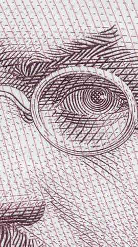 High-quality macro to wide shot transition of engraved portrait featuring detailed facial features, beard and glasses on authentic Ukrainian currency note with protective elements