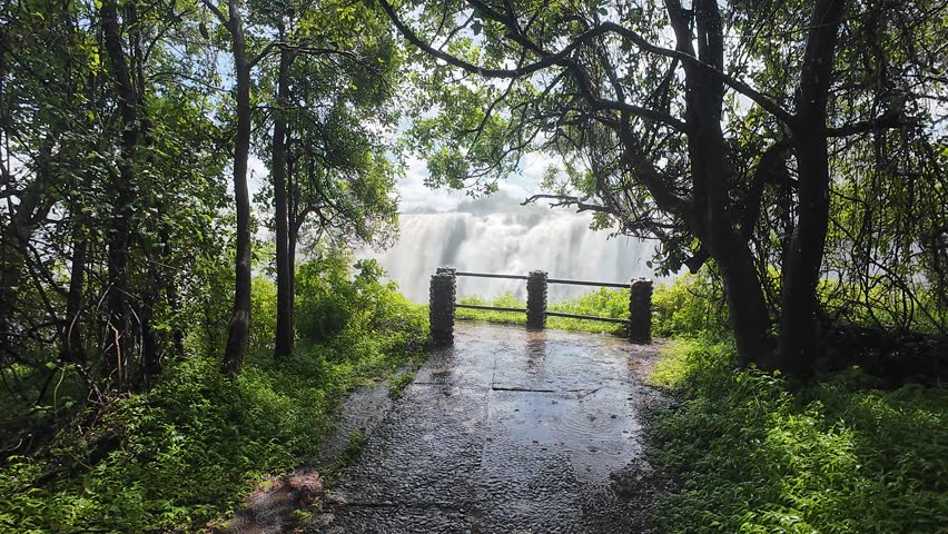 A wet pathway through forest under rain leading to the Victoria Falls at the daytime in Zimbabwe