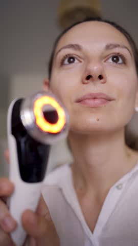 Woman using EMS lifting and LED light therapy device for facial contouring and skincare