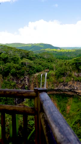 Slow motion of Chamarel Waterfall in Mauritius cascading into a forested gorge under a bright blue sky