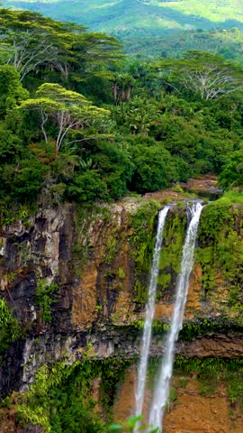 Slow motion of Chamarel Waterfall in Mauritius cascading into a forested gorge under a bright blue sky