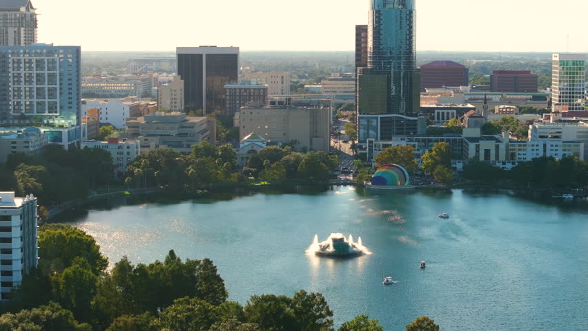 Orlando city in Florida with waterfront office and condo buildings and Lake Eola Park recreational area. Development of housing in USA.