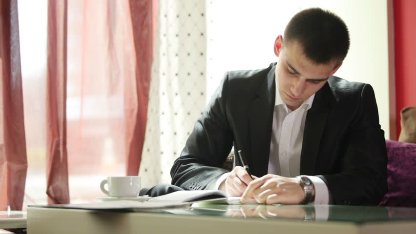 Young man writing something  and looking the time
