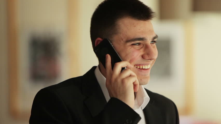 Young man with phone looking at the camera and smiling
