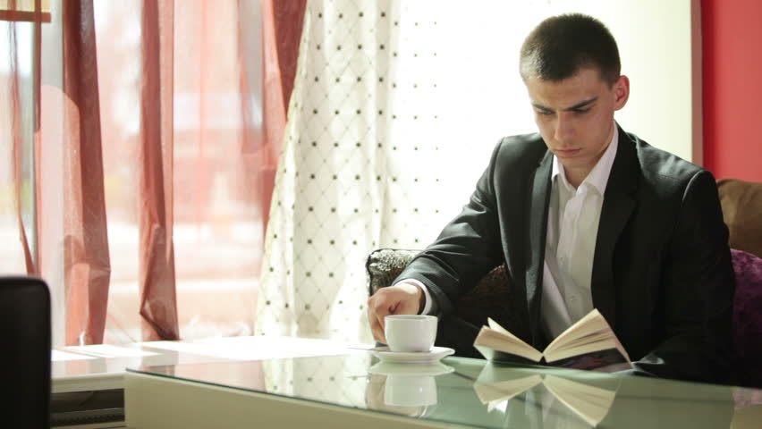 Young man drinking coffee and reading a book
