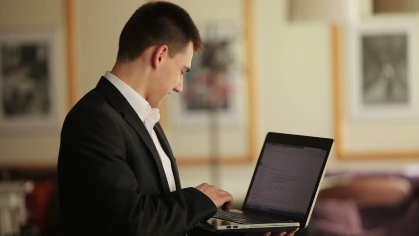 Young man with notebook typing something and smiling
