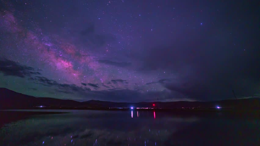 Timelapse The Lake Under the Galaxy. The Milky Way begins its graceful rise above the lake, casting its reflection upon the vast, tranquil lake below. a silent symphony of earth, water, and stars.