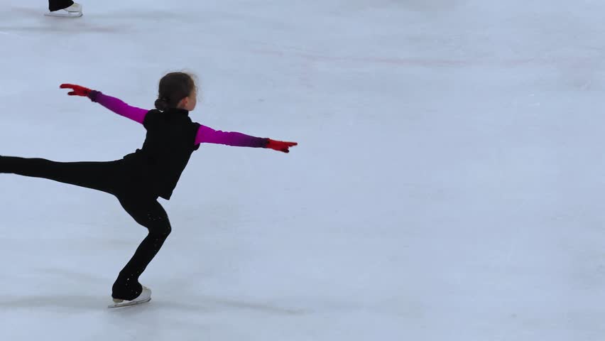 Figure skating lesson. Figure skaters training at the ice rink. Professional sports. Teenage figure skaters study and practice the elements on the ice. A girl spinning on ice.