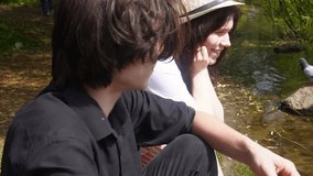 A young happy couple feeds ducks on the shore of a pond in a summer park. Summer weekend in the city. - Powered by Shutterstock - Get 15% off with code: PIKWIZARD15