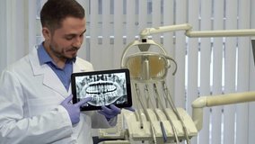 Confident dentist points at x-ray on tablet in modern clinic - Powered by Shutterstock - Get 15% off with code: PIKWIZARD15