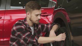 Young man examining wheels and tires of a new car at the dealership - Powered by Shutterstock - Get 15% off with code: PIKWIZARD15