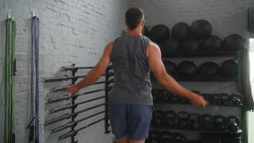 Mid adult athletic man selecting jump rope from equipment wall in modern functional training gym with white brick interior preparing for intense cardio workout routine - Powered by Shutterstock - Get 15% off with code: PIKWIZARD15