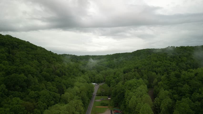 Aerial over rural road in Julien West Virginia forest with low clouds in morning in spring