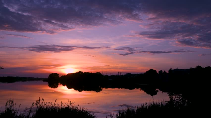 Beautiful purple clouds flying over the lake at sunset