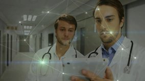 Two doctors reviewing records in hospital corridor while tapping tablet and showing network overlay. Medical team, collaboration, digital healthcare, modern technology, clinical environment, - Powered by Shutterstock - Get 15% off with code: PIKWIZARD15