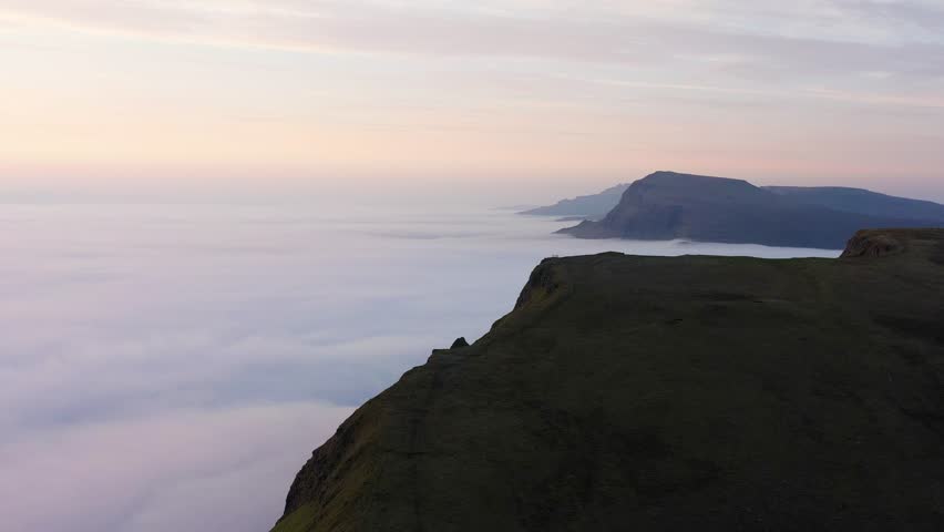 Campers in tents, camping above the clouds at sunrise on the Quiraing Isle of Skye, Scotland - Mountains piercing though the clouds as the sun rises over the horizon 