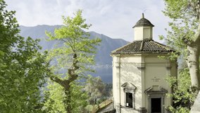 Scenic early morning views of Lake Como and the surrounding mountains from the pilgrimage path of Sacro Monte di Ossuccio, Italy, with olive trees, rooftops, and soft sun rays piercing the clouds - Powered by Shutterstock - Get 15% off with code: PIKWIZARD15