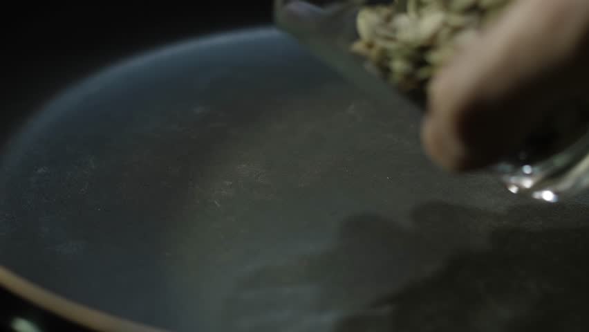 This is a detailed closeup sequence that showcases the process of toasting raw pumpkin seeds in a skillet, effectively demonstrating how to prepare delicious and healthy ingredient for various dishes